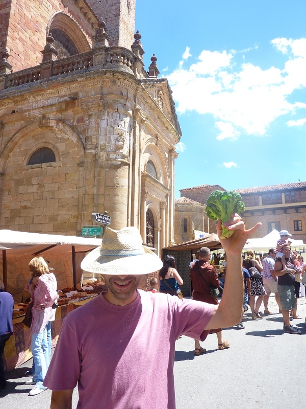 Un moderno horticultor muestra orgulloso un ejemplar de brócoli de no excesivas dimensiones, con el fondo del mercado de Sigüenza