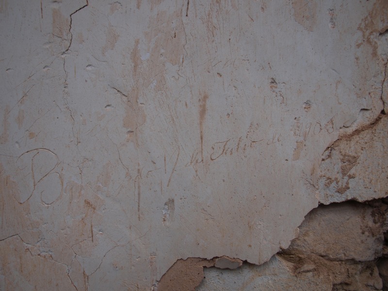 Escritura esgrafiada sobre el yeso de la pared