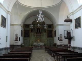 Vista interior de la iglesia, con el retablo al fondo y algunos cuadros repartidos por las paredes
